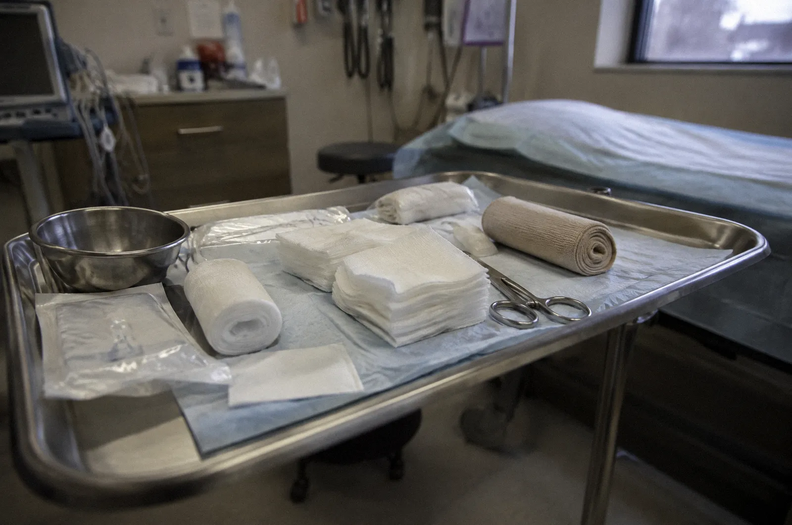 Sterile gauze and bandage supplies laid out on a clinic tray, clinical light, nothing graphic