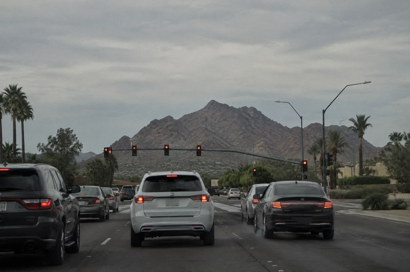 Camelback Mountain seen across a wide Phoenix-area arterial road with cars waiting at a red light