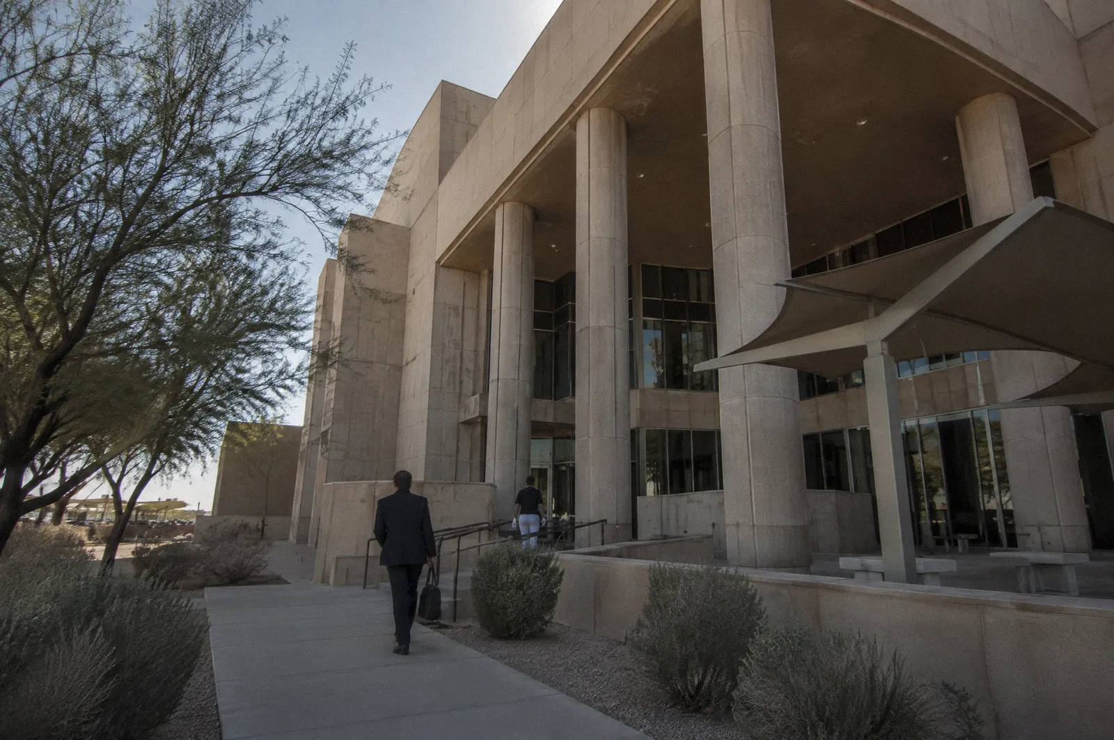 A modern desert-toned courthouse exterior with tall columns and shade structures, midday, no readable lettering