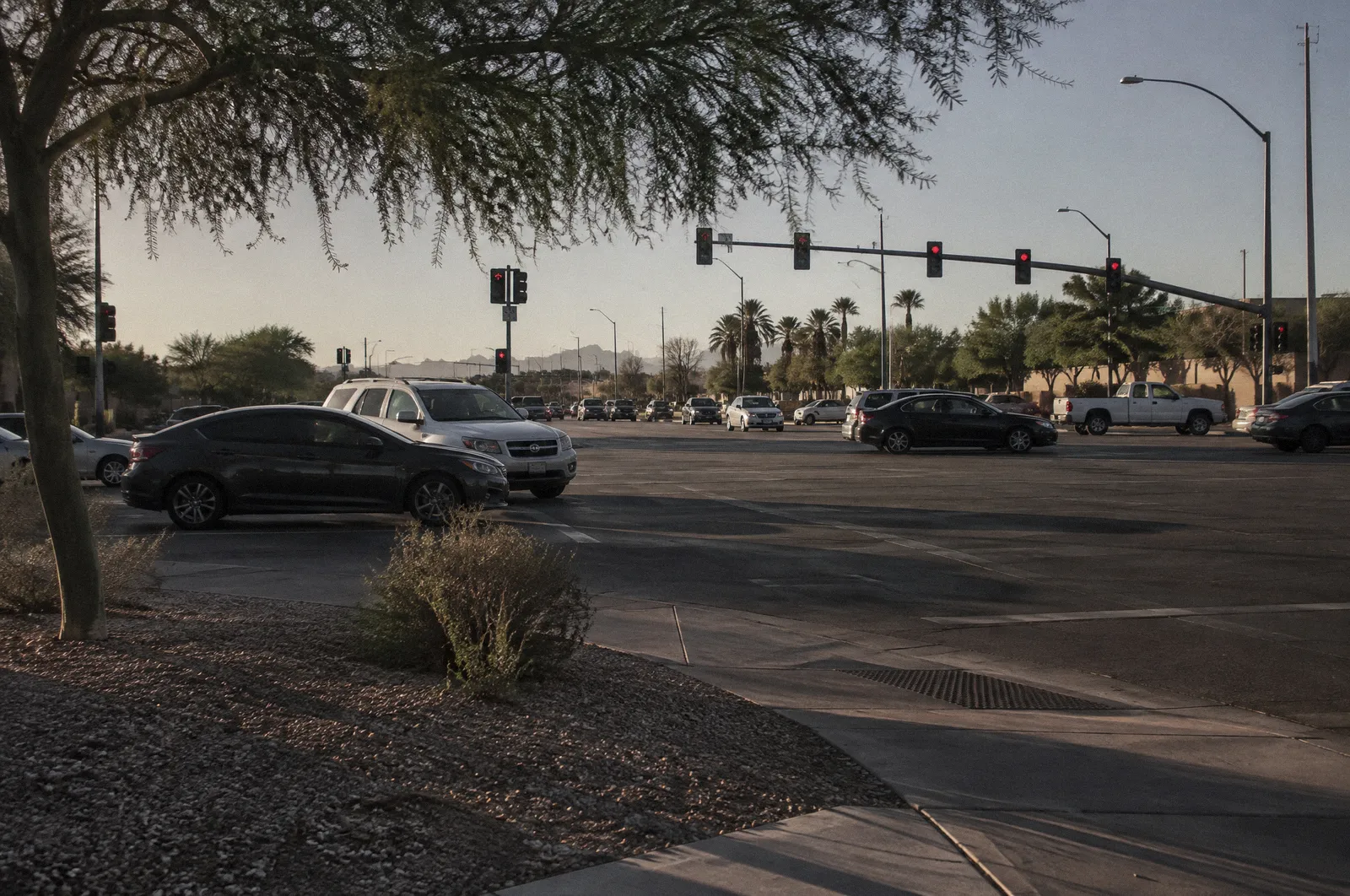 A large Phoenix-area intersection with left-turn lanes and mast-arm traffic signals on red, cars waiting