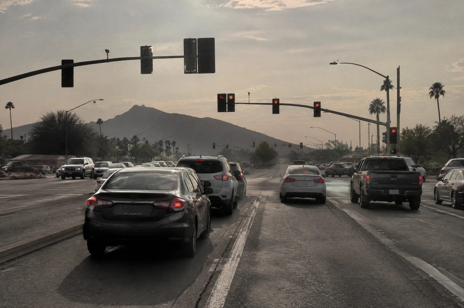 A large Phoenix-area intersection with left-turn lanes and mast-arm traffic signals on red, cars waiting