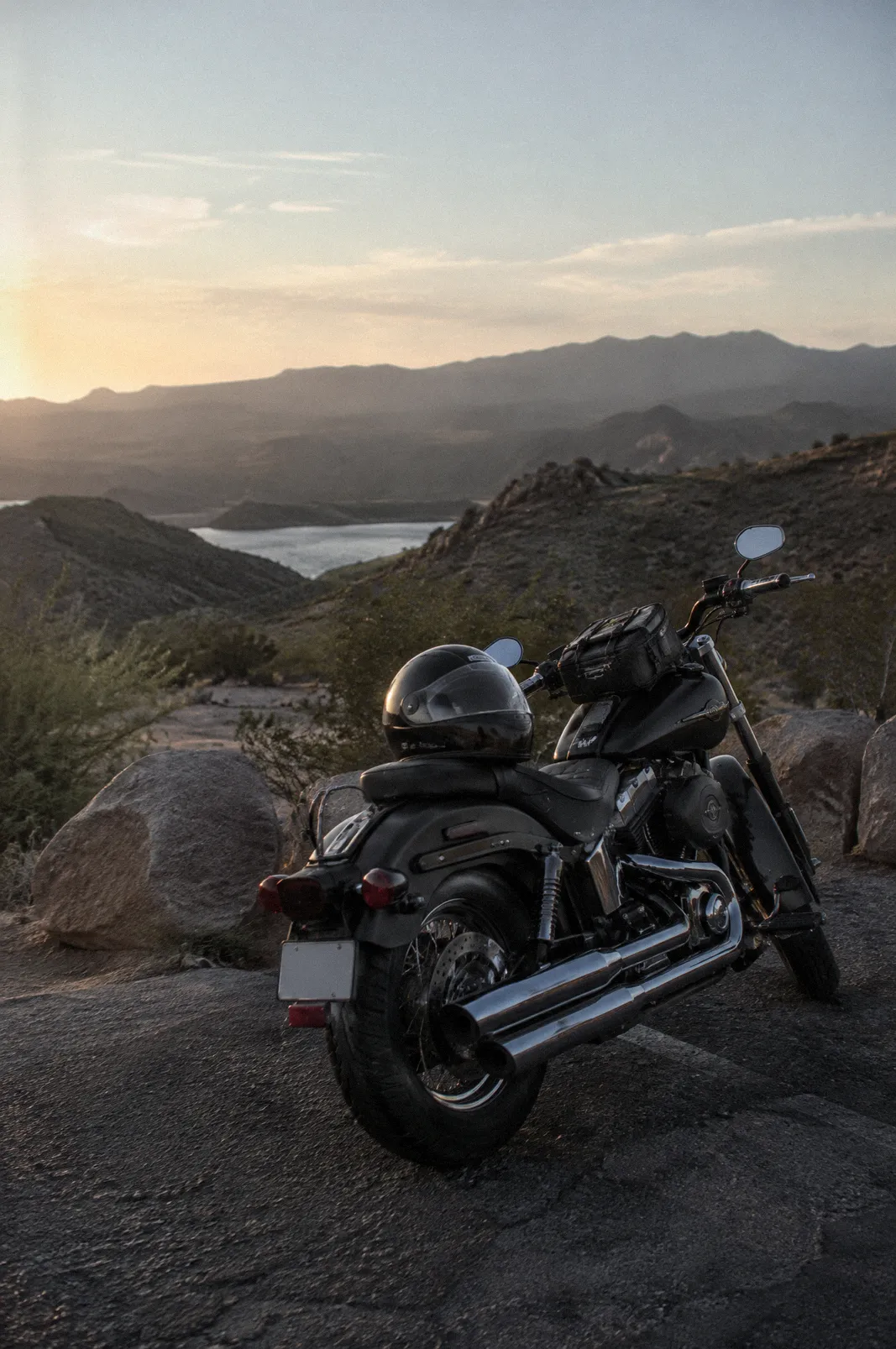 A cruiser motorcycle parked at a desert overlook, helmet on the seat, late afternoon