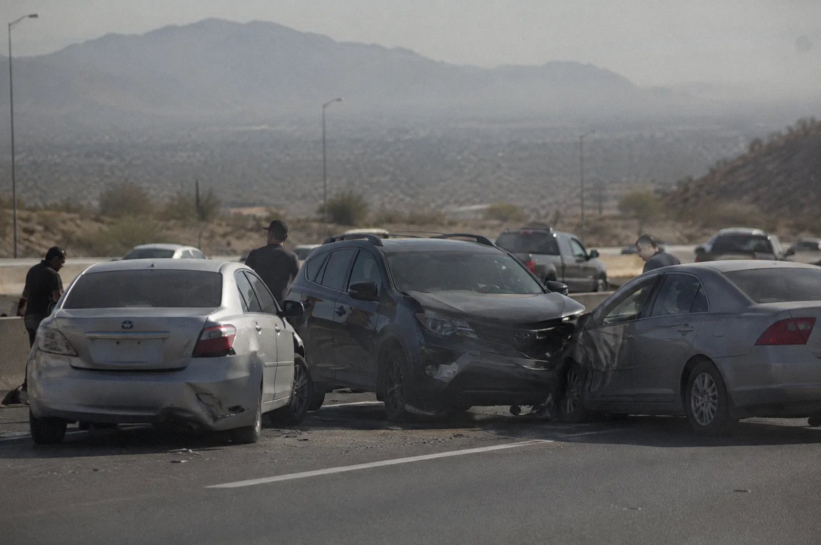 Three cars stopped at odd angles after a chain-reaction collision on a freeway, long lens, haze