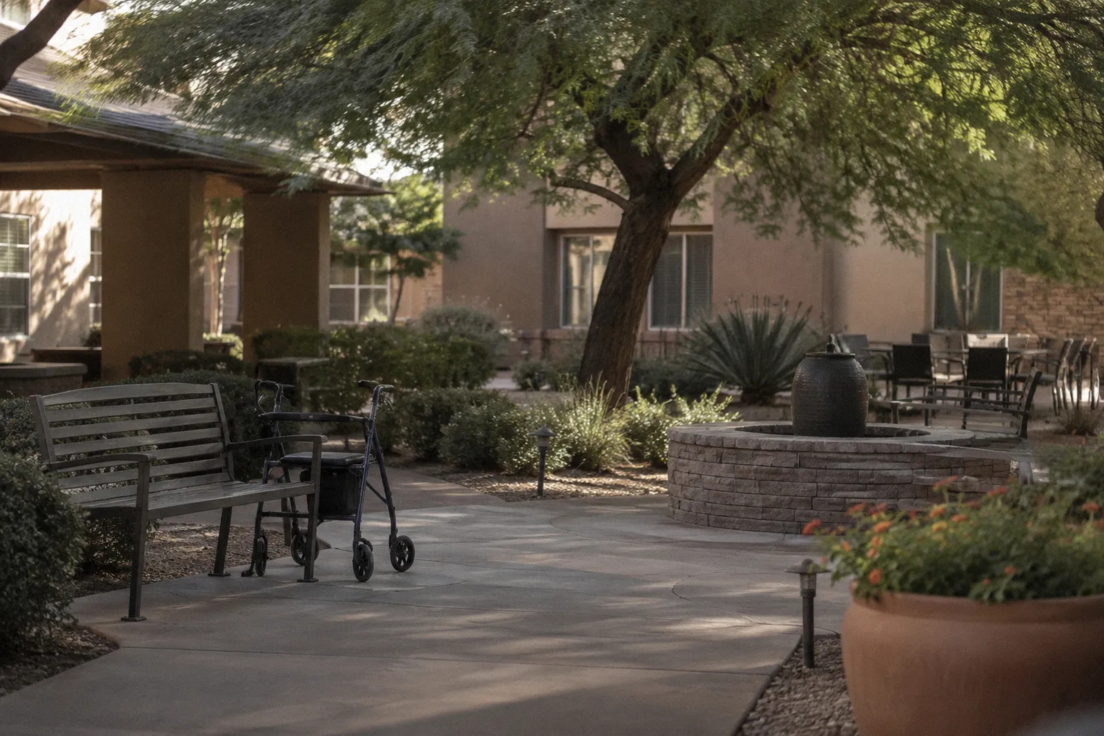 The courtyard garden of a senior care facility in Arizona with shaded benches, a walker beside a bench, no people