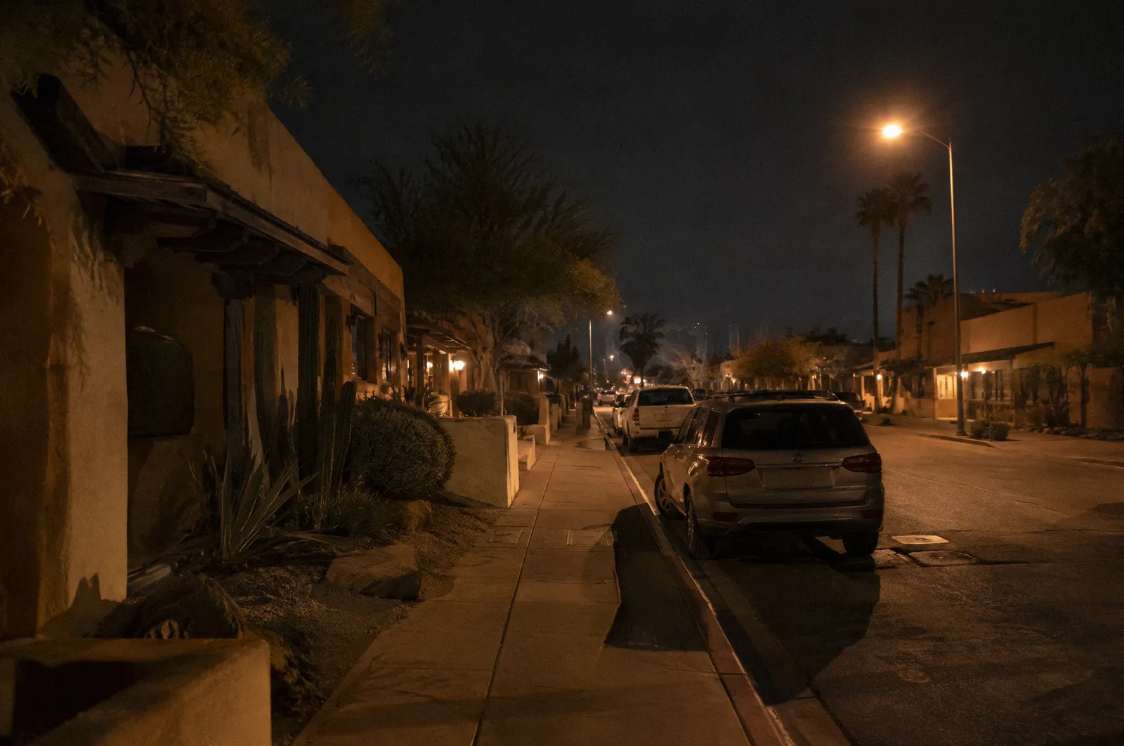 An empty Old Town Scottsdale side street early morning, low adobe-style storefronts with blank facades, desert landscaping, parked cars