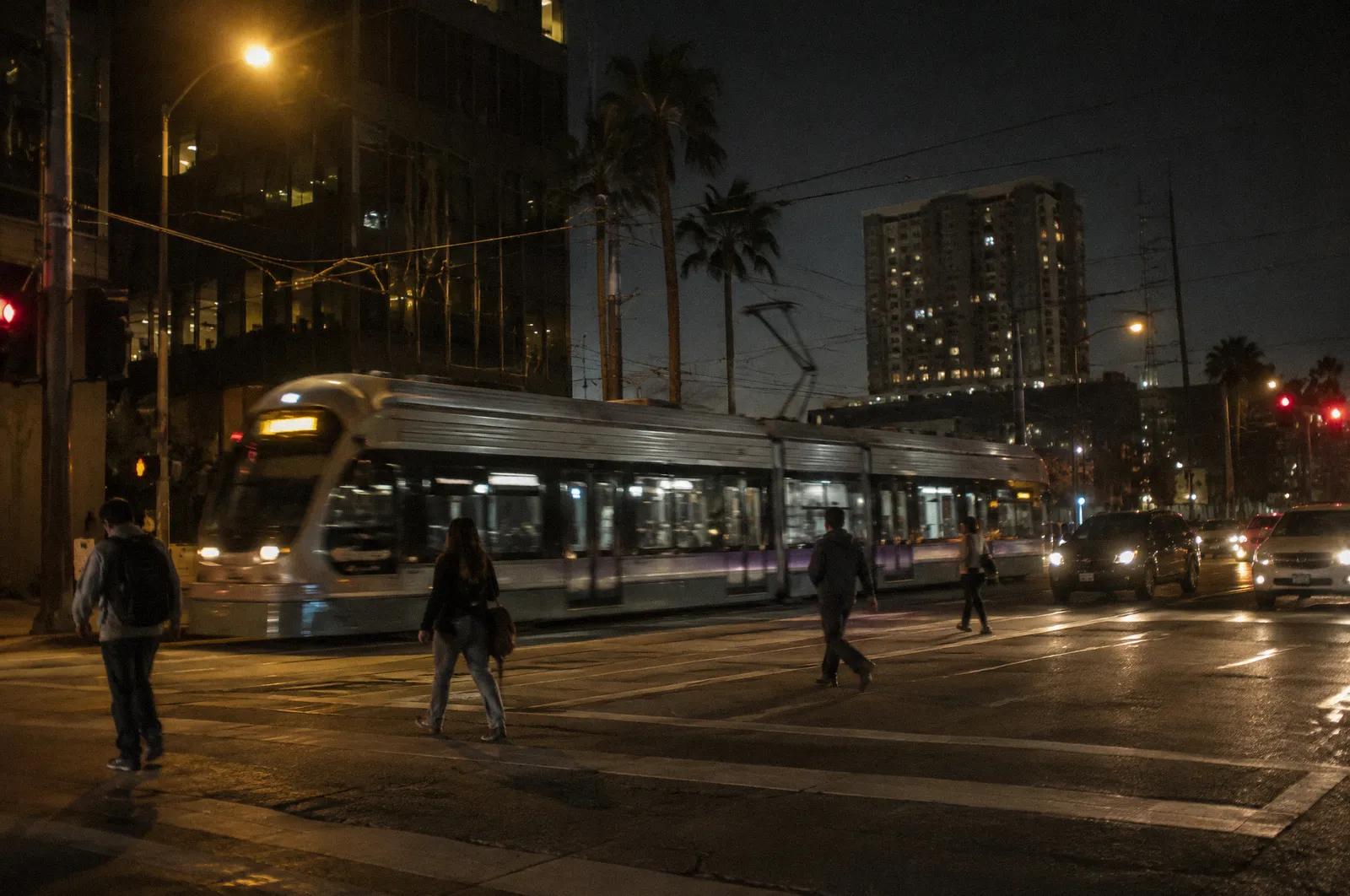A Valley Metro style light rail train passing a crosswalk in Phoenix, motion blur, no readable text on the train