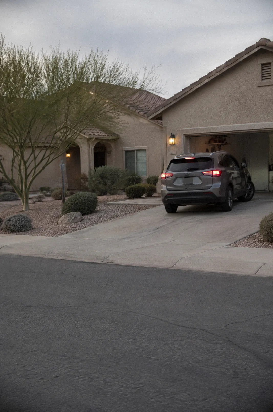 A West Valley suburban street with stucco homes and a desert-landscaped yard, a car backing out of a driveway